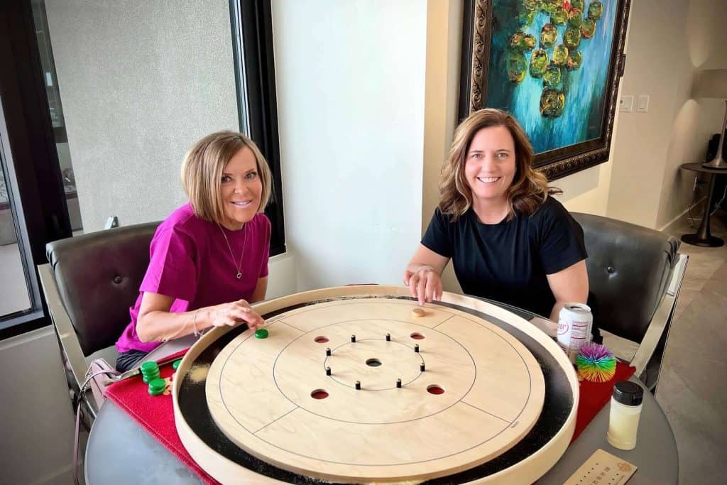 Two crokinole players at a 5-hole Tracey board