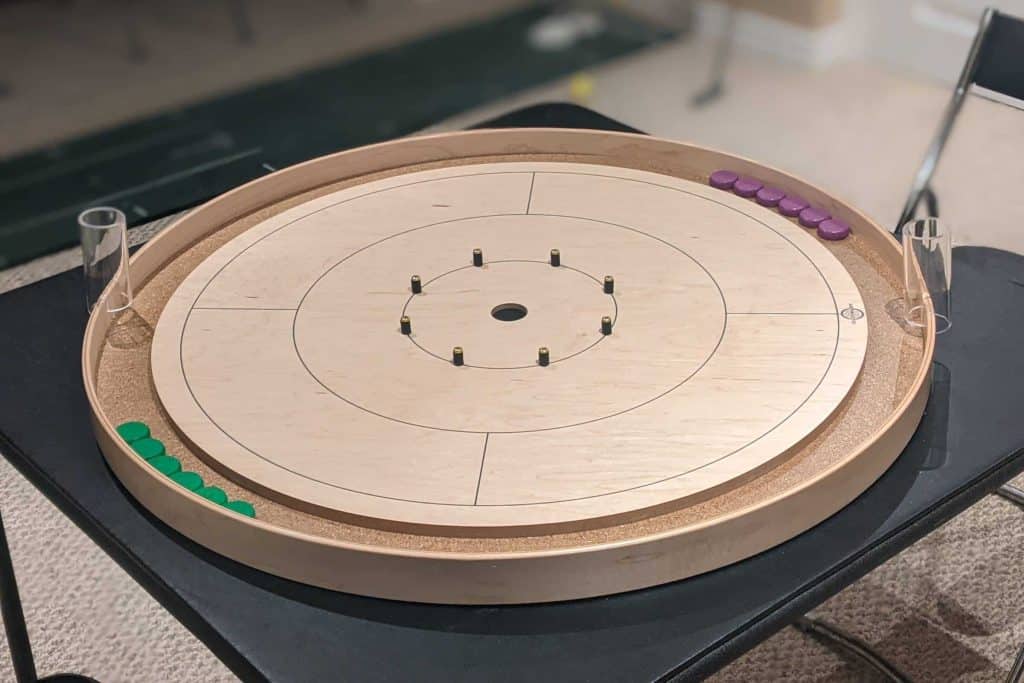 Purple and green crokinole buttons on a traditional Tracey crokinole board