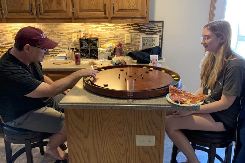 Father and daughter playing crokinole on a cherry leaf Tracey crokinole board